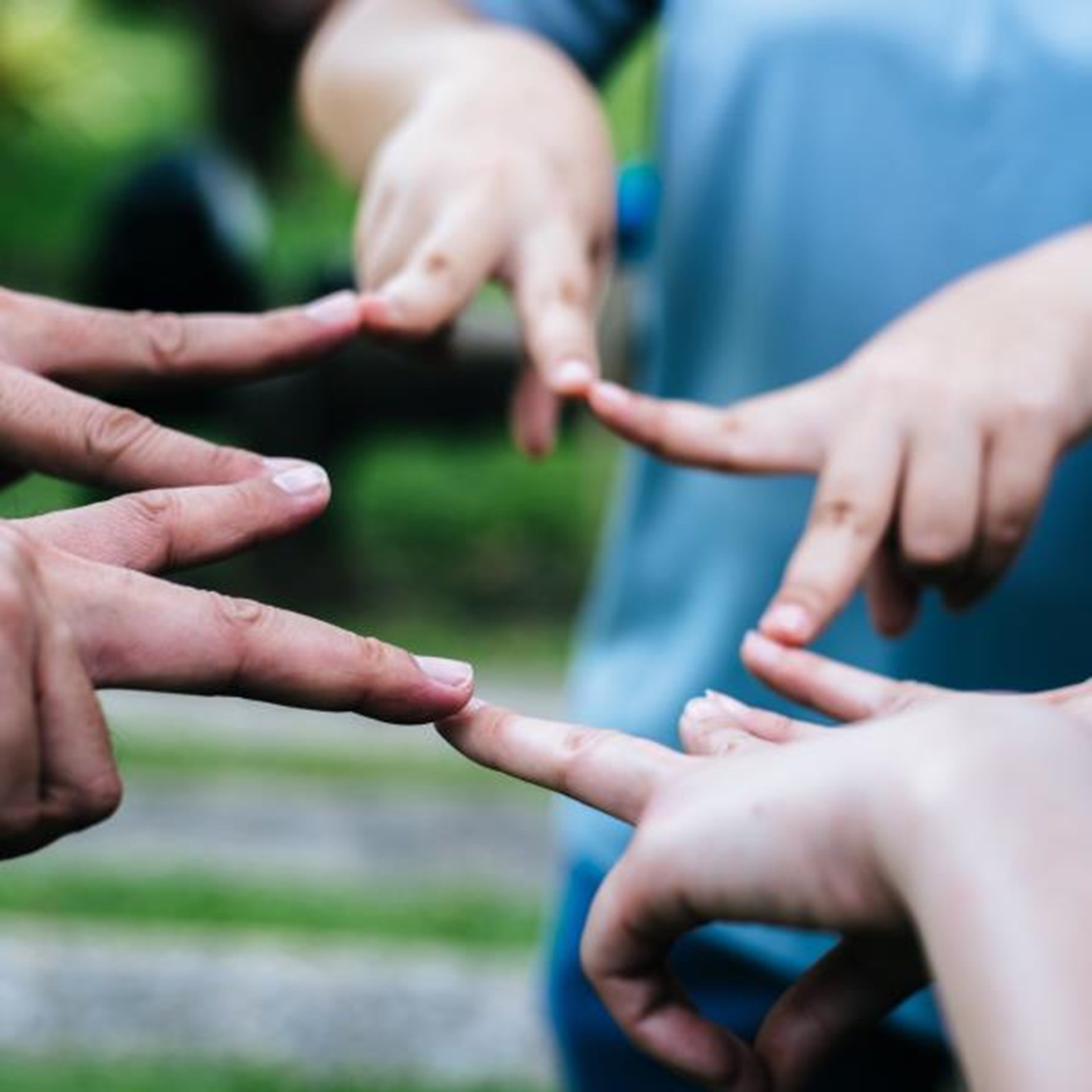 Mehrere Hände, die sich mit ausgestreckten Fingern berühren, symbolisieren Gemeinschaft und Zusammenarbeit
