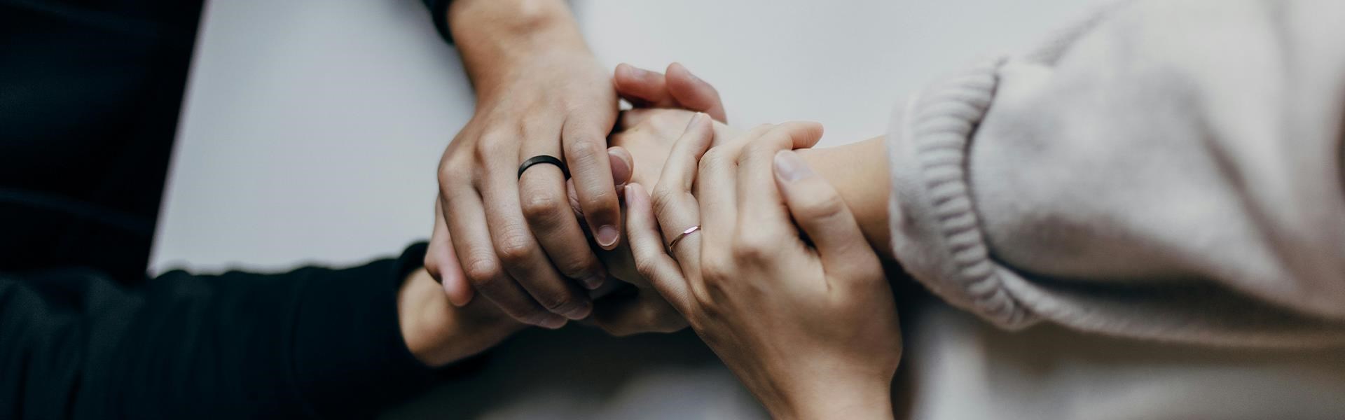 Zwei Personen halten sich einfühlsam an den Händen, Zeichen von Unterstützung und Solidarität