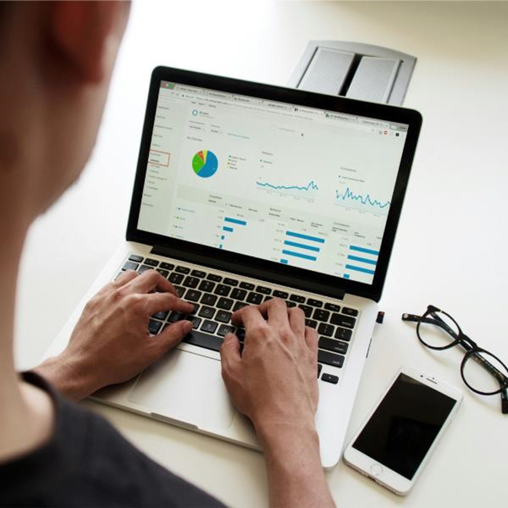 Person arbeitet an einem Laptop mit geöffneten Statistiken und Diagrammen auf dem Bildschirm