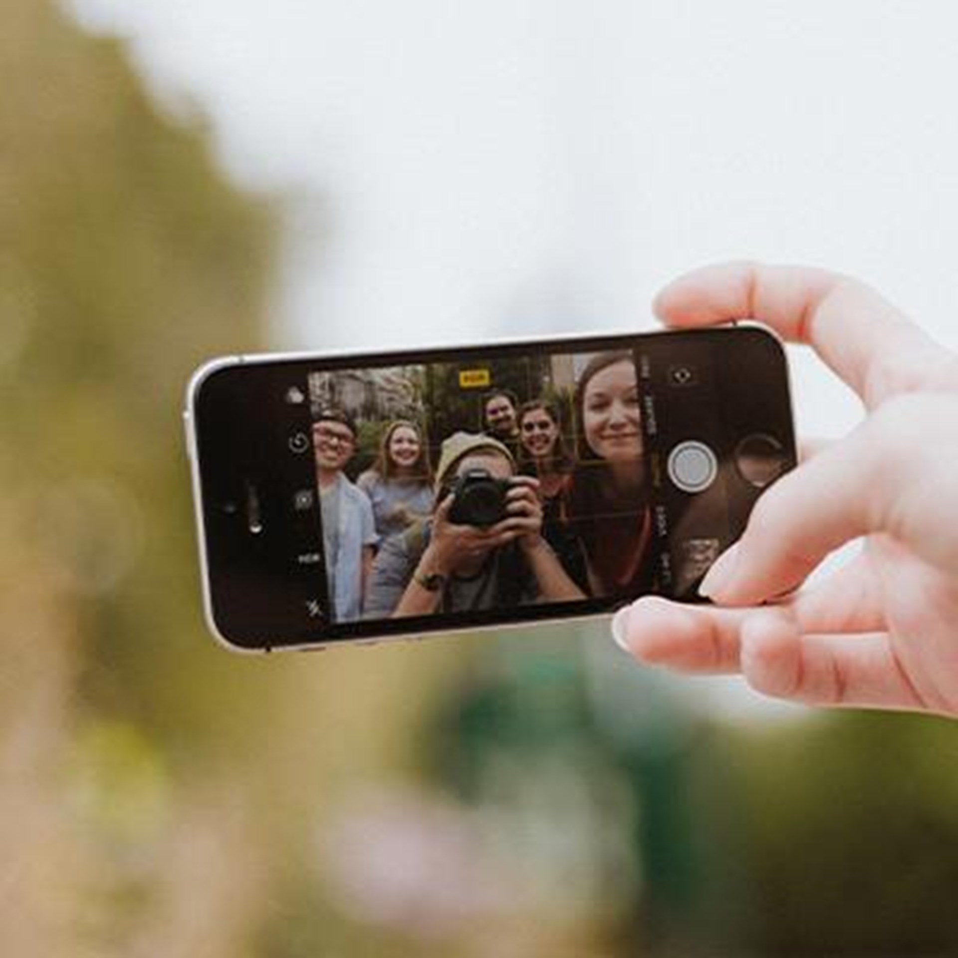 Nahaufnahme eines Smartphones, das eine Gruppe von sechs Personen zeigt, die gemeinsam ein Selfie machen.